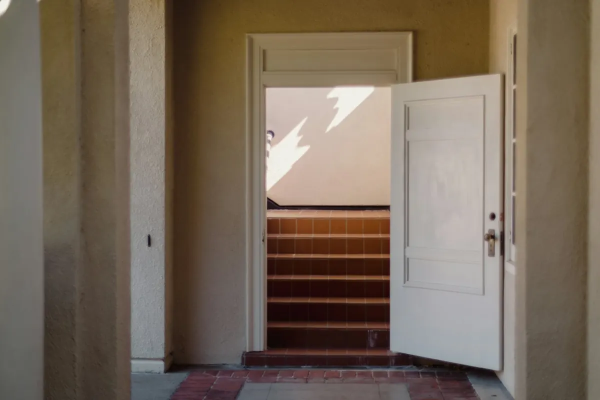 Une porte d’entrée entrouverte sur un escalier